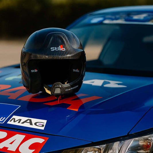 Casque stilo WRC carbone homologué posé sur le capot d'une voiture de course.