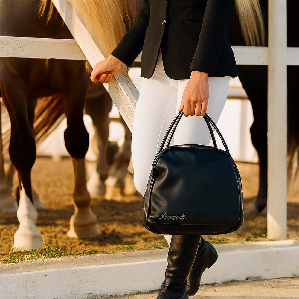 Sac de transport AURAK sans couture porté à la main par une cavalière dans un haras.