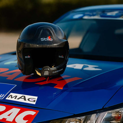 Casque stilo WRC carbone homologué posé sur le capot d'une voiture de course.