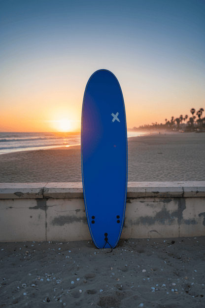 Planche de surf softboard Random X 7'0" appuyée contre un mur de plage au coucher de soleil – Les Etoiles de Magalie